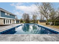 A refreshing in-ground pool sits next to a blue two story house with a pool house behind the pool at 1107 Leisure Ln, Greenwood, IN 46142