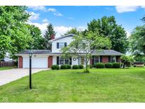 Charming two-story home with manicured lawn, mature trees, and classic brick accents under a blue sky at 1917 Remington Pl, Indianapolis, IN 46227
