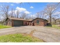 Brick home featuring attached garage, large driveway, beautiful architectural details, and mature trees at 5344 Tincher Rd, Indianapolis, IN 46221