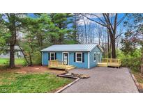 Charming blue home featuring a metal roof, dark shutters, and newly constructed wooden porches in a wooded lot at 7469 Lion Dr, Nineveh, IN 46164