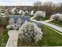 Stunning aerial view of a two-story brick home with beautiful flowering trees and a well-maintained lawn in a suburban neighborhood at 805 Harvest Lake Dr, Brownsburg, IN 46112