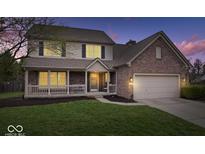 Charming two-story brick home with a covered porch, well-manicured lawn, and a two-car garage, perfect for Gathering living at 10889 Weston Dr, Carmel, IN 46032