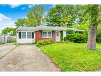 Charming single story home with red brick and white siding, green lawn and partial driveway at 11416 Stoeppelwerth Dr, Indianapolis, IN 46229