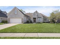 Charming, light brick home with an attached garage and meticulously maintained front yard at 11930 Pebblepointe Pass, Carmel, IN 46033