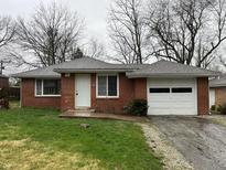 Charming brick home featuring a one-car garage and a well-maintained front lawn at 1509 N Mann Ave, Muncie, IN 47304