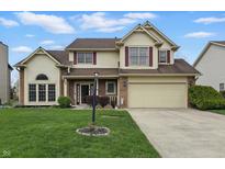 Classic two-story house featuring a manicured lawn, attached garage, and inviting entrance with a lamppost at 5710 Dapple Trce, Indianapolis, IN 46228