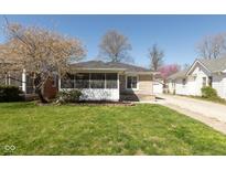 Charming stone home featuring a cozy screened-in porch and well-manicured lawn at 6120 Norwaldo Ave, Indianapolis, IN 46220