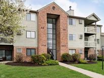 Inviting condo complex with brick facade, well-maintained lawn, and mature landscaping for a welcoming curb appeal at 7220 Village Parkway Dr # 8, Indianapolis, IN 46254