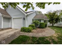 Charming home featuring light blue siding, attached garage, and meticulously landscaped front yard at 9029 Crook N Dr, Indianapolis, IN 46256