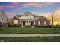 Beautiful two-story brick home with a manicured lawn, twin front doors, and a cozy front porch at 13974 Nina Dr, Carmel, IN 46074