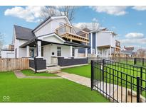 A charming two-story home with a black brick foundation, a deck, and a fenced front yard at 415 S Oxford St, Indianapolis, IN 46201