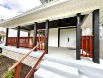 Inviting front porch with grey steps, wooden railing, and white columns with black accents leads to the main entrance at 625 N Parker Ave, Indianapolis, IN 46201