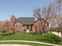 Charming brick home features a well-manicured lawn and mature trees, creating a welcoming curb appeal at 7322 Franklin Parke Ct, Indianapolis, IN 46259