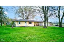 A quaint yellow home with a well-maintained yard and a detached garage, framed by mature trees at 7764 S State Road 109, Markleville, IN 46056