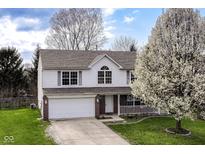 Charming two-story home with a well-manicured lawn, inviting porch, attached garage, and beautiful flowering trees at 8424 Nuckols Ln, Indianapolis, IN 46237