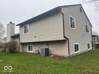 Back exterior view of home with siding, showing backyard lawn and chimney at 10047 Lone Wolf Dr, Indianapolis, IN 46235