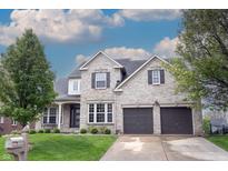 Beautiful two-story brick home featuring a two-car garage, well-manicured lawn, and mature trees at 10365 Aurora Ct, Fishers, IN 46038