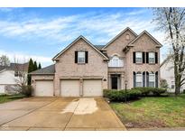 Charming two-story brick home featuring a three-car garage and manicured lawn at 12479 Autumn Gate Way, Carmel, IN 46033