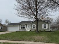 Charming single story home with green lawn and a two-car garage, enhanced by a mature shade tree at 1424 Ashley Dr, Lebanon, IN 46052
