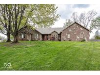 Charming brick home features a lush green lawn, mature trees, and a welcoming red front door at 1509 Copperwood Pl, Carmel, IN 46033
