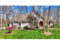 Charming exterior featuring manicured lawn, stone facade, and arched entryway with red door at 23219 Marin Dr, Cicero, IN 46034