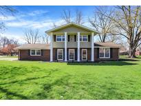 Charming two-story home with a brick facade, lush green lawn, and beautiful trees on a sunny day at 5311 Larita Ln, Anderson, IN 46017