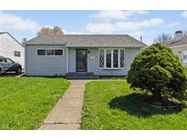 Charming home featuring a well-maintained front lawn, gray siding and an inviting walkway leading to the front door at 5427 E 19Th St, Indianapolis, IN 46218