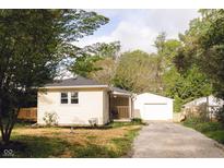 Charming home featuring a detached garage, wood deck, and gravel driveway lined with trees at 5820 Bonnie Brae St, Indianapolis, IN 46228