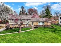 Beautifully landscaped home with a stone and siding exterior and a lush green lawn at 6377 Green Leaves Rd, Indianapolis, IN 46220