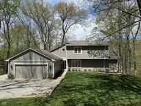 Charming two-story home with attached garage and a lush green lawn in a serene, wooded setting at 7809 S Solitude Ln, Trafalgar, IN 46181