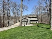 Charming gray two-story home featuring a lush green lawn, attached garage, and mature trees at 7809 S Solitude Ln, Trafalgar, IN 46181