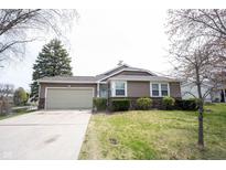 Charming one-story home with a two-car garage, a well-maintained lawn, and lush landscaping in a serene setting at 8075 N Cardinal W Cv, Indianapolis, IN 46256