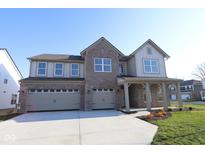 Inviting two-story home featuring a three-car garage, brick accents, and a covered front porch at 10543 Banyan Wood Ct, Indianapolis, IN 46239
