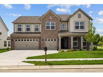 Charming two-story home with a brick facade, three-car garage, and well-manicured lawn at 10543 Banyan Wood Ct, Indianapolis, IN 46239