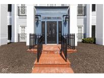 Inviting building entrance features red brick steps, a black door, and blue accents at 12926 University Cres # 2C, Carmel, IN 46032