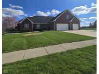 Charming brick home features a two-car garage, manicured lawn, and a blooming tree at 1513 Tottenham Dr, Danville, IN 46122