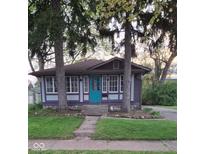 Charming single-story home with a turquoise door, stone foundation and mature trees at 213 S Brittain Ave, Muncie, IN 47303