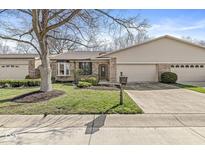 Charming brick home with a well-maintained lawn, mature tree, and attached two-car garage at 8433 Quail Hollow Rd, Indianapolis, IN 46260