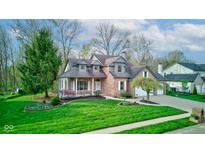 Charming two-story home with brick facade, covered porch, manicured lawn, and attached two-car garage at 8695 Shoe Overlook Dr, Fishers, IN 46038
