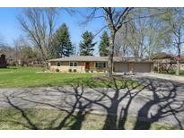 Charming single-story home featuring a stone facade, manicured lawn, and mature trees providing ample shade at 1750 W Stop 11 Rd, Indianapolis, IN 46217