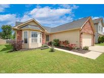 Charming home boasts a well-manicured lawn, brick accents, and a two-car garage at 2390 Lakecrest Dr, Columbus, IN 47201