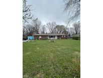 Single story red brick home with an expansive green front lawn and mature trees at 4310 42Nd St, Indianapolis, IN 46226