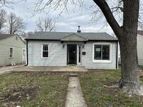 A quaint one-story home featuring horizontal siding, gray roof, a small porch and walkway leading to the entrance at 5810 Greenfield Ave, Indianapolis, IN 46219