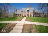 Beautiful red brick home with manicured lawn and landscaped beds and an American flag at 6013 Yellow Birch Ct, Avon, IN 46123