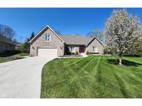 Charming brick home featuring a well-manicured lawn, mature tree, and attached two-car garage at 8717 Vintner Ct, Indianapolis, IN 46256