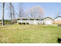 Ranch style home with a green exterior, single garage, and well-manicured lawn and landscaping at 12566 S Hillview Dr, Columbus, IN 47201