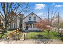Charming two-story home featuring a landscaped front yard with mature trees and an inviting front porch at 1403 Fletcher Ave, Indianapolis, IN 46203