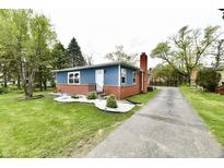 Lovely home exterior features a well-manicured lawn, brick and blue siding, and a long driveway at 1934 N Arlington Ave, Indianapolis, IN 46218