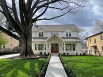Charming white two-story home with a welcoming front porch, manicured lawn, and a large shade tree at 5940 Central Ave, Indianapolis, IN 46220