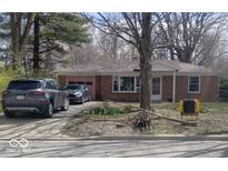 Charming single-story brick home featuring a pink garage door, lush landscaping and private driveway at 721 1St Ne Ave, Carmel, IN 46032